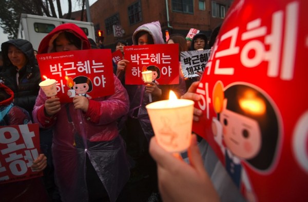 Protesters hold candles during an anti-government rally demanding the resignation of South Korea's President Park Geun-Hye in central Seoul on November 26, 2016. Tens of thousands of protesters braved sleet and freezing temperatures in Seoul on November 26 to demand President Park Geun-Hye resign over a corruption scandal or face impeachment.   / AFP PHOTO / JUNG Yeon-Je