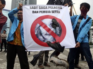 Muslim protesters throw shoes at a defaced poster of US pop singer Lady Gaga during a protest against her concert that is scheduled to be held on June 3, in Jakarta, Indonesia, Thursday, May 24, 2012. Lady Gaga might have to cancel her sold-out show in Indonesia because police worry her sexy clothes and dance moves undermine Islamic values and will corrupt the country's youth. The writing on the poster reads "Lady Gaga is a prostitute and Satan worshipper.  AP PHOTO/TATAN SYUFLANA