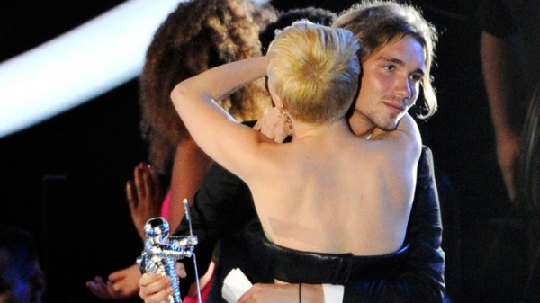 In this Sunday, Aug. 24, 2014 file photo, Miley Cyrus, front, hugs Jesse Helt, right, at the MTV Video Music Awards at The Forum in Inglewood, Calif. The young homeless man who accompanied Cyrus to the MTV Video Music Awards has a warrant out for his arrest in Oregon. Helt gained worldwide attention Sunday when Cyrus let him accept her award for video of the year. (Photo by Chris Pizzello/Invision/AP, file)