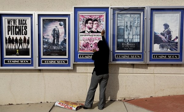 A poster for the movie "The Interview" is taken down by a worker after being pulled from a display case at a Carmike Cinemas movie theater, Wednesday, Dec. 17, 2014, in Atlanta. Georgia-based Carmike Cinemas has decided to cancel its planned showings of "The Interview" in the wake of threats against theatergoers by the Sony hackers. (AP Photo/David Goldman)