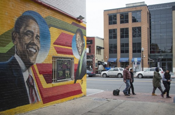 People walk past a mural of US President Barack Obama(L) and comedian Bill Cosby painted on the side of Ben's Chili Bowl in Washington, DC.