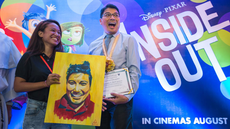 HONORED Ronald “Ronnie” del Carmen, Filipino director and cowriter of the new computer-animated Pixar film “InsideOut,” receives his portrait from a fine arts student of the University of Santo Tomas during a homecoming on his old campus on Monday. PHOTOS BY JILSON SECKLER TIU