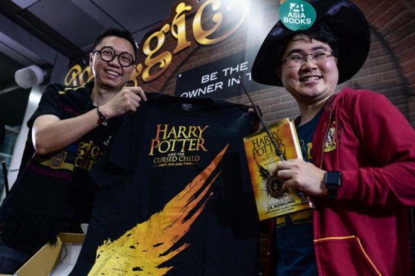 Harry Potter fan Santipat Huangsawat (R) receives the first of the new Harry Potter script book to be launched in Thailand outside Asia Books in Bangkok on July 31, 2016.  Rowling's books have sold more than 450 million copies since 1997 and been adapted into eight films. / AFP PHOTO / LILLIAN SUWANRUMPHA