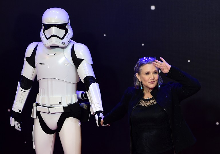 (FILES) This file photo taken on December 16, 2015 shows US actress Carrie Fisher (R) posing with a storm trooper as she attends the opening of the European Premiere of "Star Wars: The Force Awakens" in central London. A family spokesman for the said December 27, 2016 that Carrie Fisher, the iconic actress who portrayed Princess Leia in the Star Wars series, died Tuesday following a massive heart attack last week. She was 60. / AFP PHOTO / LEON NEAL