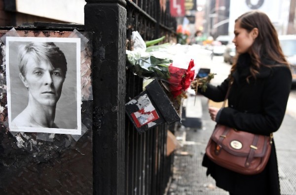 A woman places flowers outside of David Bowie's SoHo apartment building on the first anniversary of Bowie's death on January 10, 2017 in New York City. / AFP PHOTO / ANGELA WEISS