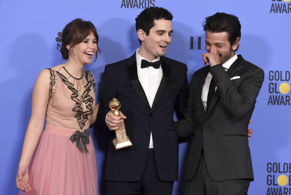Damien Chazelle, center, winner of the award for best screenplay - motion picture for "La La Land" poses with presenters Felicity Jones, left, and Diego Luna at the 74th annual Golden Globe Awards at the Beverly Hilton Hotel on Sunday, Jan. 8, 2017, in Beverly Hills, Calif. (Photo by Jordan Strauss/Invision/AP)