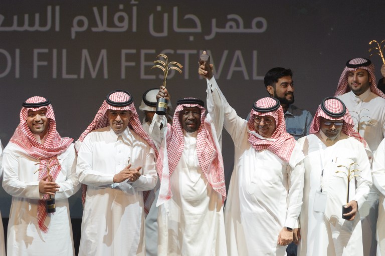 Saudi actor Saed Khader (C) waves his honour award for his achievements at the opening ceremony of the fourth Saudi Film Festival held in Dammam City, 400 kilometres east from Saudi capital Riyadh, on March 27, 2017. This year's festival is the first since the kingdom began last year a cautious push to introduce entertainment, despite opposition from Muslim hardliners. / AFP PHOTO / STRINGER