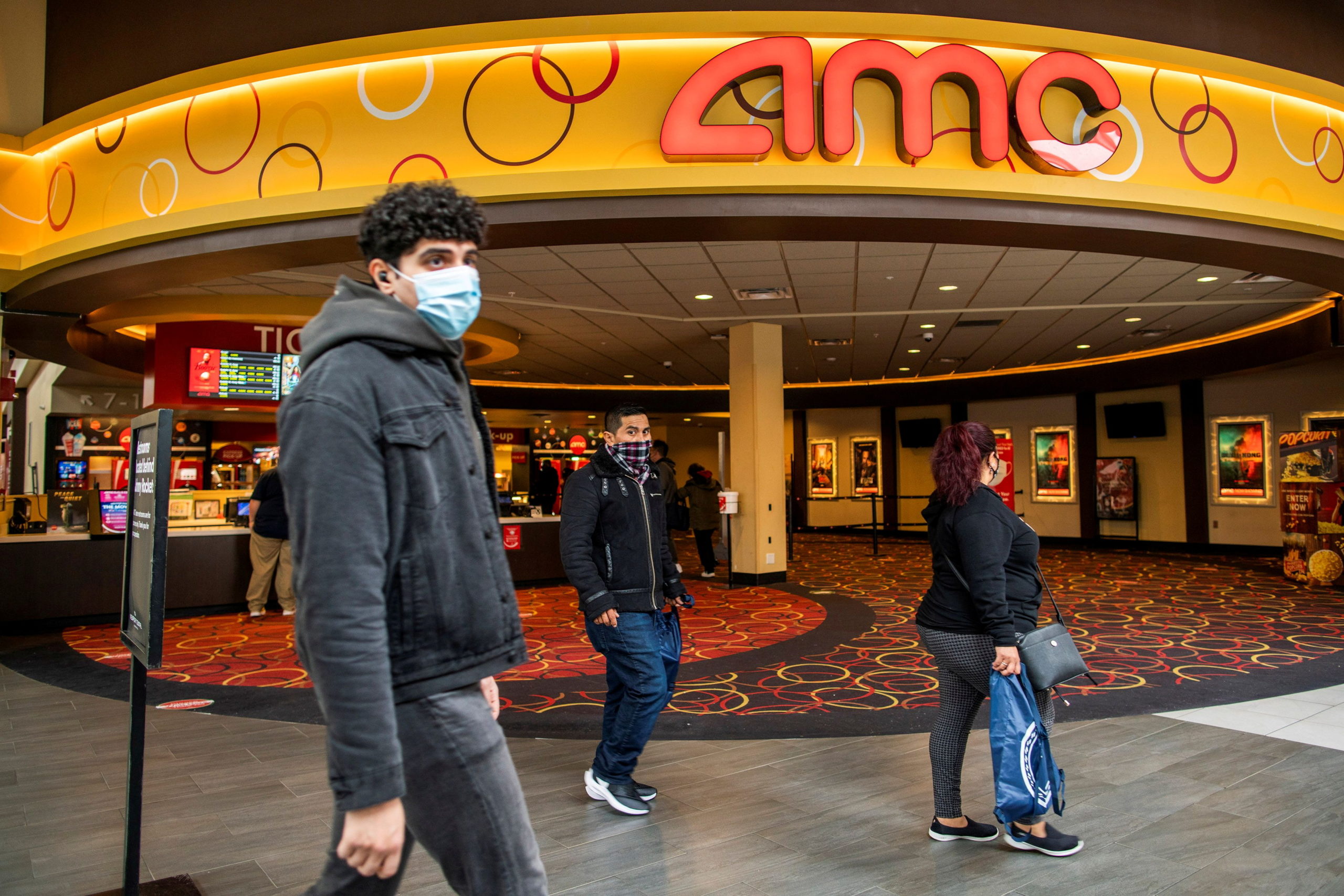 People wear face masks as they walk by a movie theater during the coronavirus disease (COVID-19) pandemic in Newport, New Jersey, U.S., April 2, 2021. REUTERS/Eduardo Munoz/File Photo