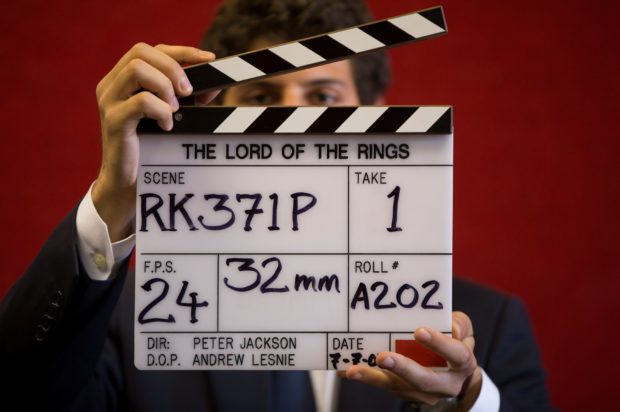 A gallery assistant poses for a photograph with a clapper board used in the filming of the Lord of the Rings film 'Return of the King' in Bonhams auction house in London