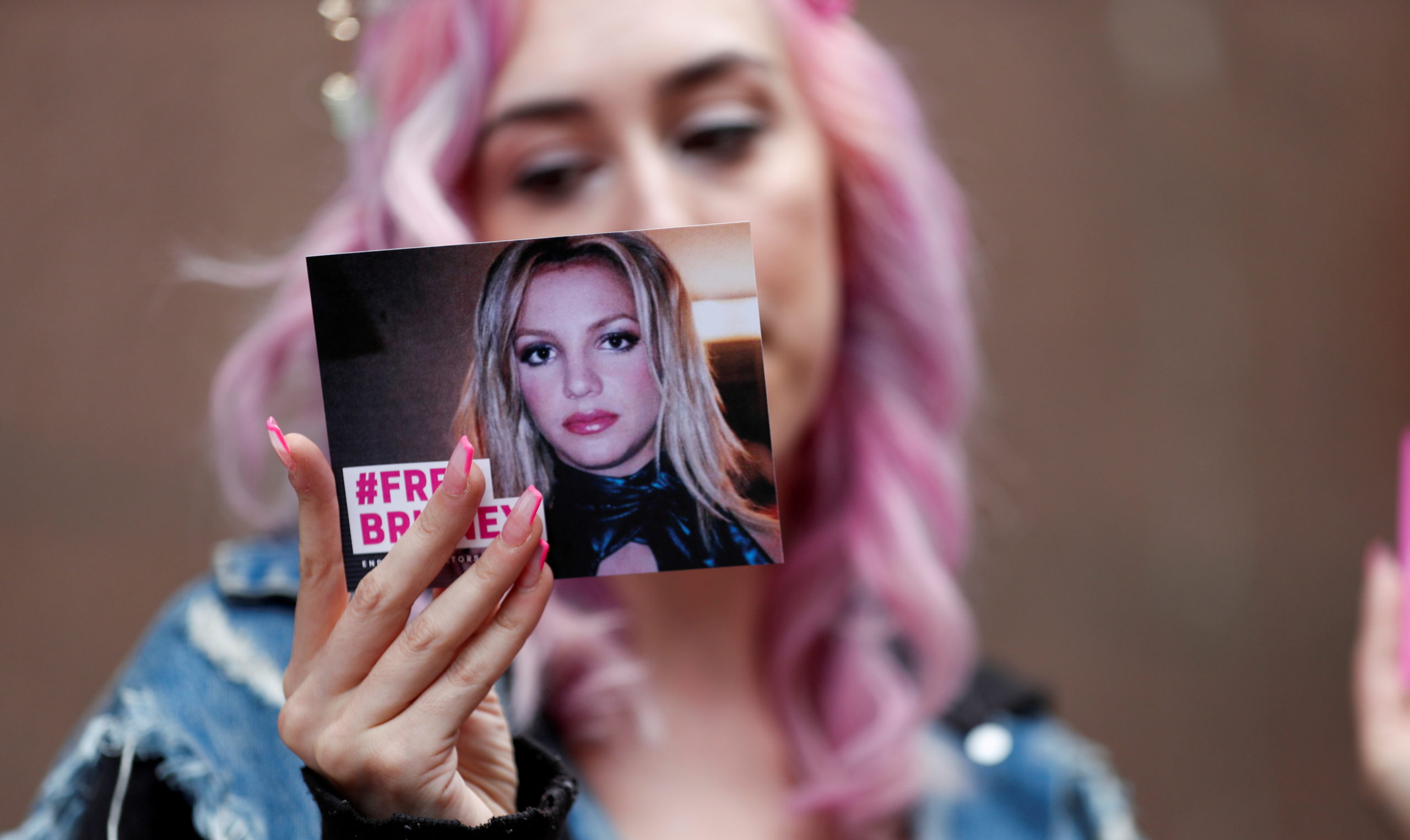 Supporter of pop star Britney Spears Melanie Mandarano holds a postcard on the day of a conservatorship case hearing at Stanley Mosk Courthouse in Los Angeles, California, U.S., July 26, 2021.  REUTERS/Mario Anzuoni