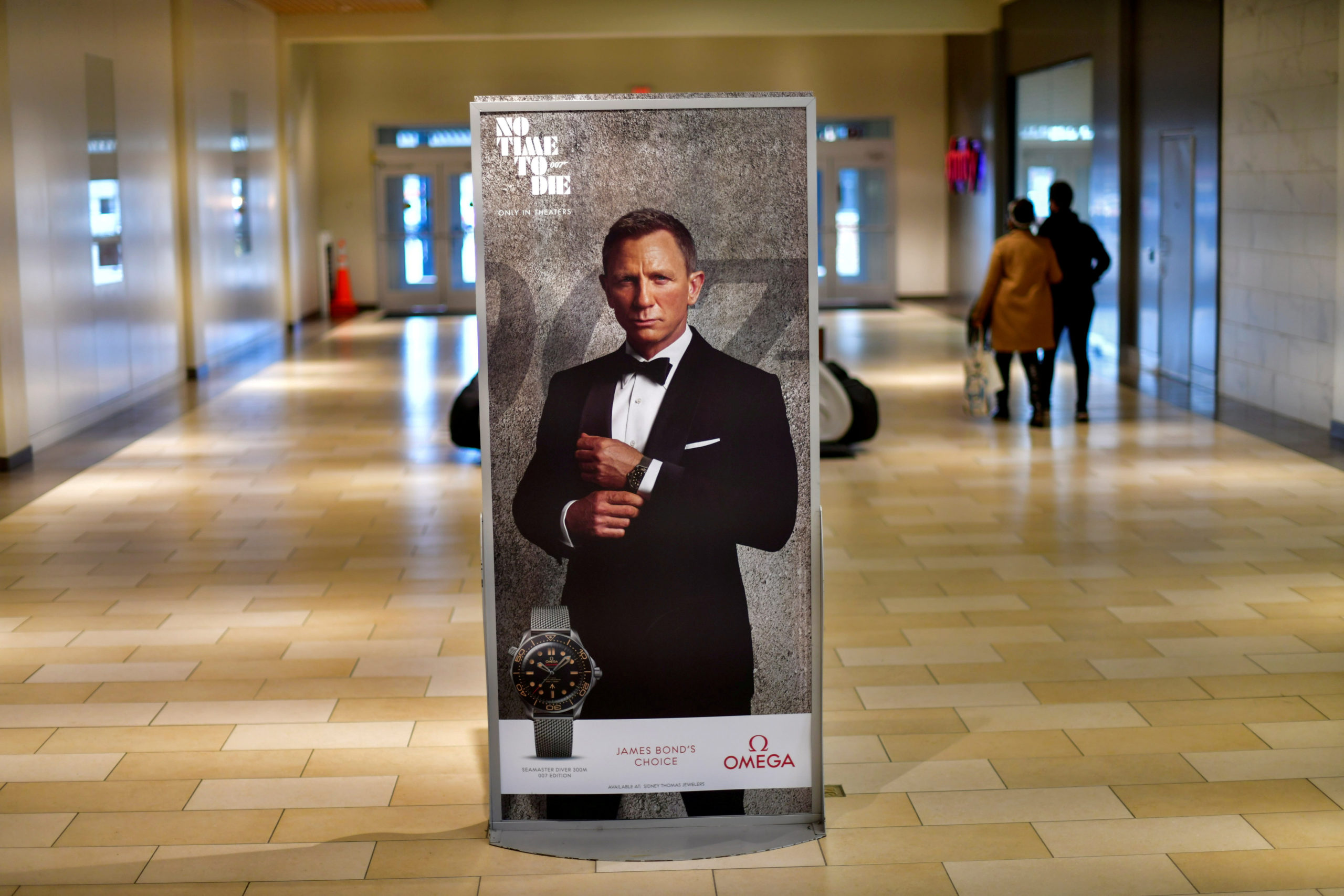 Shoppers walk past an advertisement for the upcoming James Bond film "NO TIME TO DIE" whose release has been delayed to October, at the Christiana Mall in Newark, Delaware U.S. November 19, 2020. 