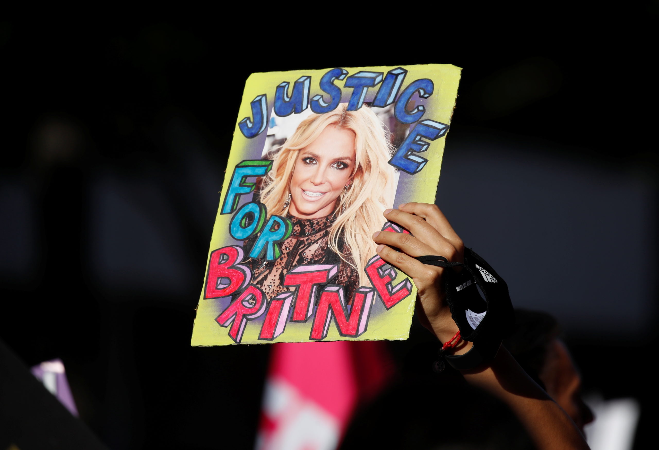A supporter of singer Britney Spears holds up a picture of the pop star with the words "Justice for Britney" during celebrations for the termination of her conservatorship, outside the Stanley Mosk Courthouse in Los Angeles, California, U.S. November 12, 2021. REUTERS/Mike Blake