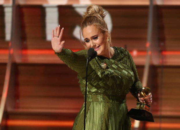 FILE PHOTO: Adele waves to singer Beyonce who is in the audience as she and co-song writer Greg Kurstin (not pictured) accept the Grammy for Song of the Year for "Hello" at the 59th Annual Grammy Awards in Los Angeles, California, U.S. , February 12, 2017. REUTERS/Lucy Nicholson/File Photo