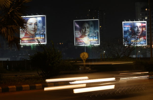 Traffic moves past a poster of upcoming Indian film "Jalsa" on a street in Mumbai