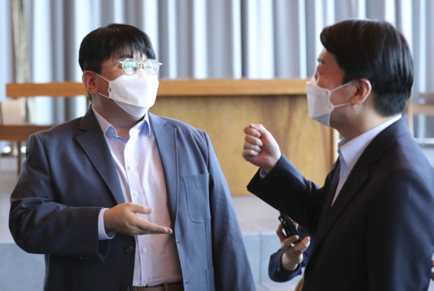 Hybe Chairman Bang Si-hyuk (left) talks with the presidential transition committee’s Chairman Ahn Cheol-soo at the company’s office in Seoul on Saturday