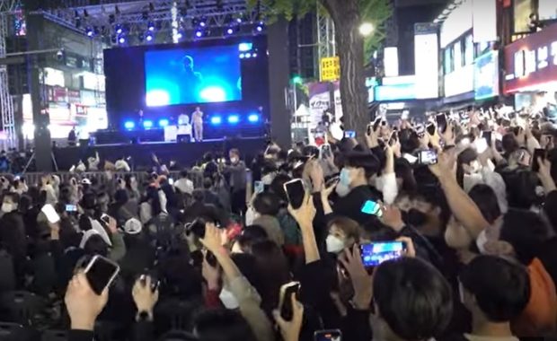 A screenshot shows the 4.19 Revolution National Cultural Festival, in which a crowd of people wave their smartphones and sing along to Korean hip-hop duo Dynamic Duo on the stage