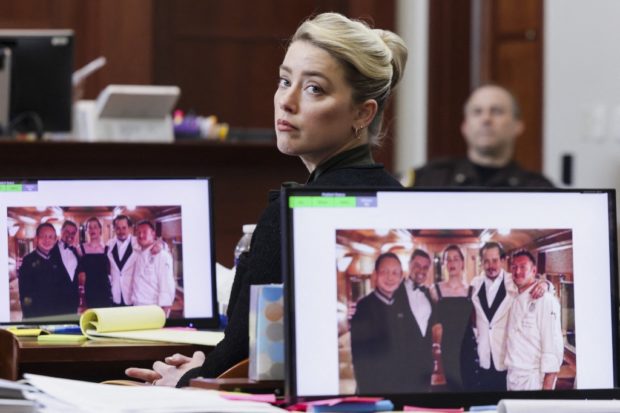 A picture introduced into evidence of actor Johnny Depp and his ex-wife actor Amber Heard with the staff of the Orient Express train taken at the end of their honeymoon trip in Singapore after their wedding in 2015, is displayed on the screens during Depp's defamation trial against his ex-wife Amber Heard, at the Fairfax County Circuit Courthouse in Fairfax, Virginia, on May 25, 2022. - Actor Johnny Depp is suing ex-wife Amber Heard for libel after she wrote an op-ed piece in The Washington Post in 2018 referring to herself as a public figure representing domestic abuse. (Photo by EVELYN HOCKSTEIN / POOL / AFP)