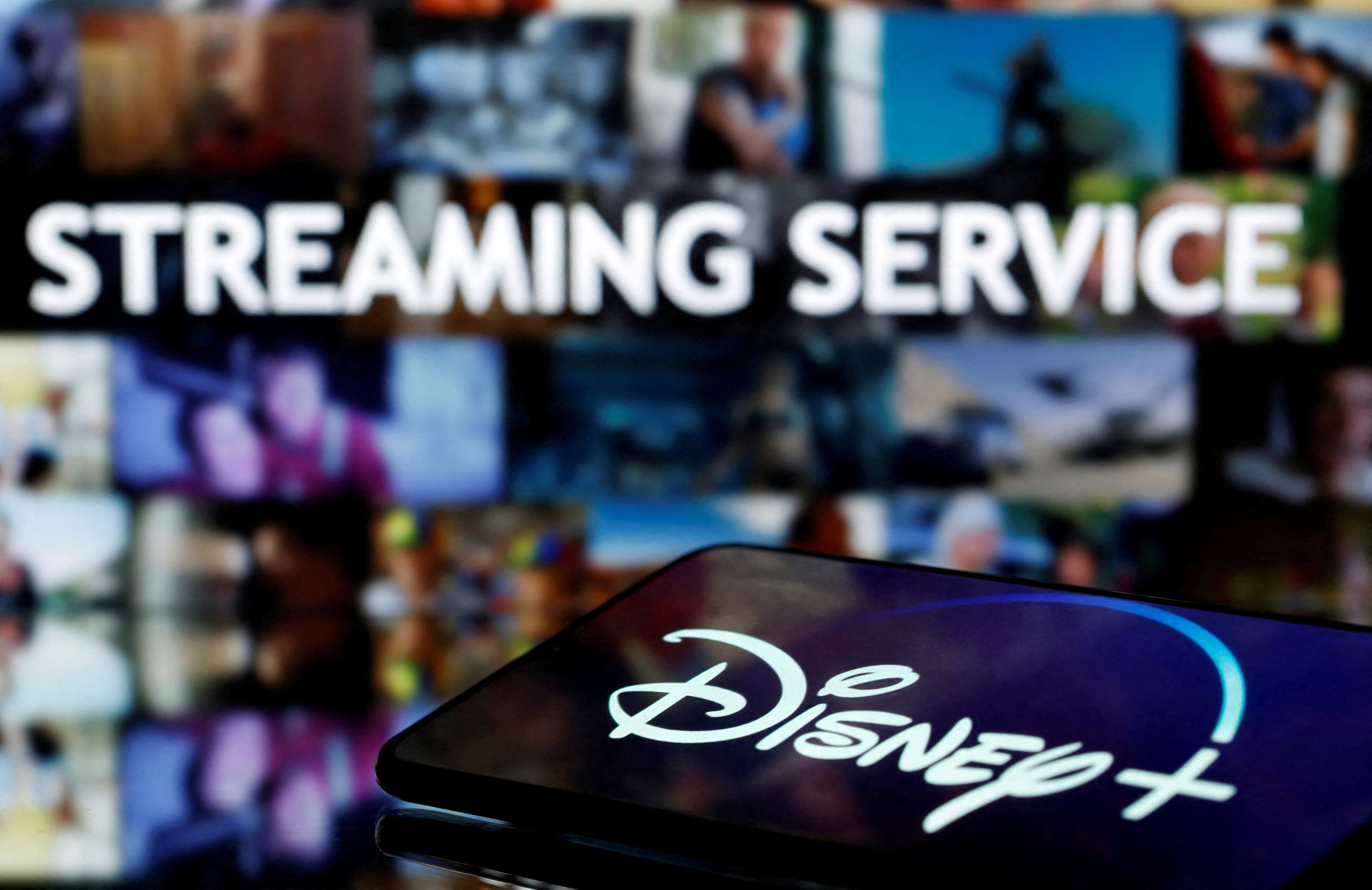 A smartphone screen showing the "Disney+" logo is seen in front of the words "streaming service" in this illustration taken March 24, 2020. REUTERS/Dado Ruvic