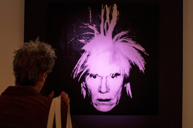 FILE PHOTO: A man examines "Self-Portrait" by Andy Warhol during a media preview at Christie's auction house in New York, October 31, 2014. REUTERS/Brendan McDermid/File Photo