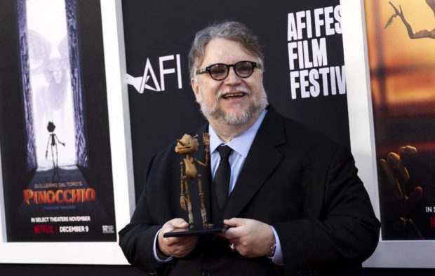 (FILES) In this file photo taken on November 05, 2022, Mexican director Guillermo del Toro holds a wooden puppet as he arrives for the premiere of "Pinocchio" during the 2022 American Film Institute Festival at the TCL Chinese Theatre in Hollywood, California. - When Guillermo del Toro first set out to make a dark, animated version of "Pinocchio" 15 years ago, he opted to set his tale of puppets and their string-pulling masters in 1930s fascist Italy. But in "Guillermo del Toro's Pinocchio," out on Netflix next month, they find themselves living in Benito Mussolini's inter-war world of military salutes, strict conformity, and violent machismo. (Photo by AUDE GUERRUCCI / AFP)