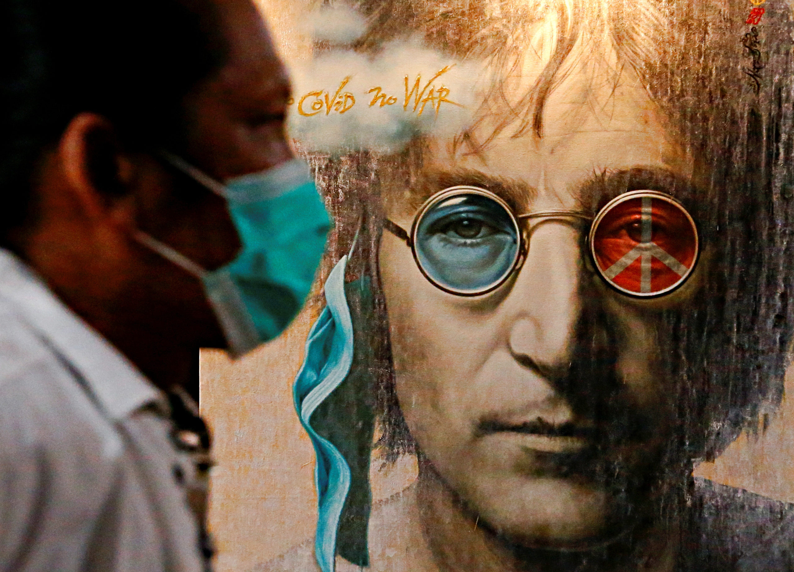 A visitor wearing a protective face mask walks past painted art depicting John Lennon during an exhibition, amid the coronavirus disease (COVID-19) outbreak, in Jakarta, Indonesia, October 15, 2020. REUTERS/Ajeng Dinar Ulfiana/File Photo