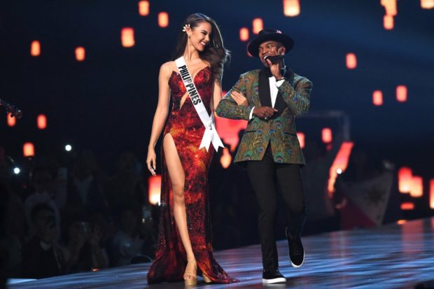 Top three finalist Catriona Gray (L) of the Philippines looks on while US artist Ne-Yo performs on stage during the 2018 Miss Universe Pageant in Bangkok on December 17, 2018. (Photo by Lillian SUWANRUMPHA / AFP)