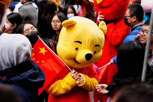 FILE PHOTO: A parade participant in a Winnie the Pooh costume waves a Chinese flag before the Lunar New Year parade celebrating the Year of the Rabbit in the Chinatown neighborhood of New York, U.S., February 12, 2023. REUTERS/Bing Guan