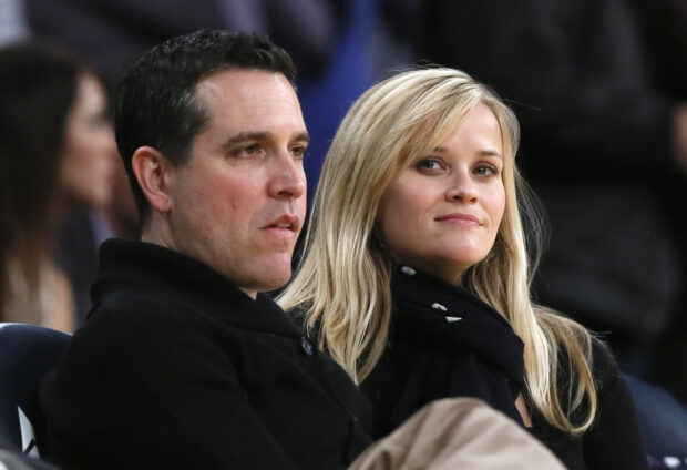 Reese Witherspoon and her husband Jim Toth watch the Toronto Raptors play the Los Angeles Lakers in their NBA basketball game in Los Angeles, March 8, 2013. 
