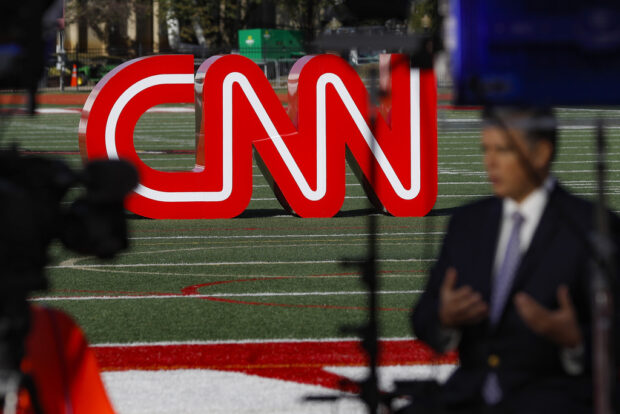 FILE - A journalist records video near a CNN sign on an athletic field outside the Clements Recreation Center where the CNN/New York Times will host the Democratic presidential primary debate at Otterbein University, Monday, Oct. 14, 2019, in Westerville, Ohio.   Mark Thompson was appointed as chair and CEO of CNN by David Zaslav, head of the network's parent company, Warner Bros. Discovery, which made the announcement Wednesday, Aug. 30, 2023. Thompson replaces Chris Licht, who was fired in June, and a four-person team that had been running CNN in the interim. (AP Photo/John Minchillo, File)