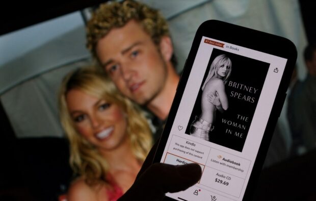 Britney Spears' book "The Woman in Me" from an online retailer in front of a picture of Britney Spears and Justin Timberlake.jpg