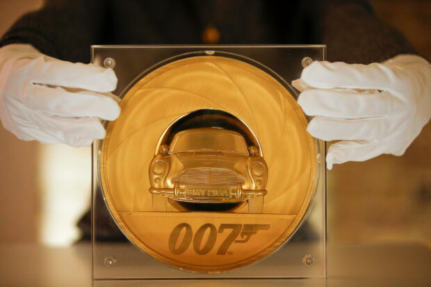 An assistant poses with the James Bond 007 Special Issue 2020 UK Seven-Kilo Gold Proof Coin, the largest coin ever made by The Royal Mint, in London