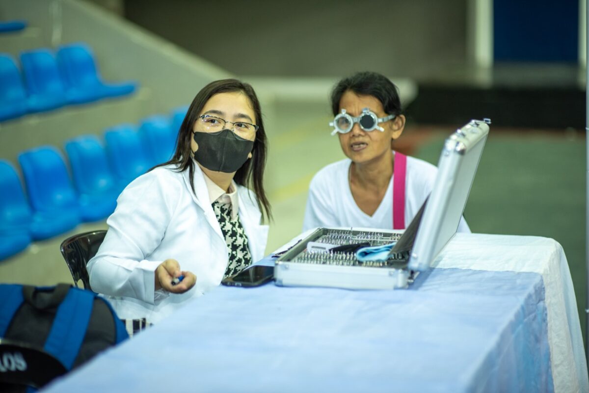 An optometrist carefully examines the eyesight of an elderly woman during MR.DIY's “Big and small, Kita Mo!” Optical Mission, providing essential eye care services to the local community.