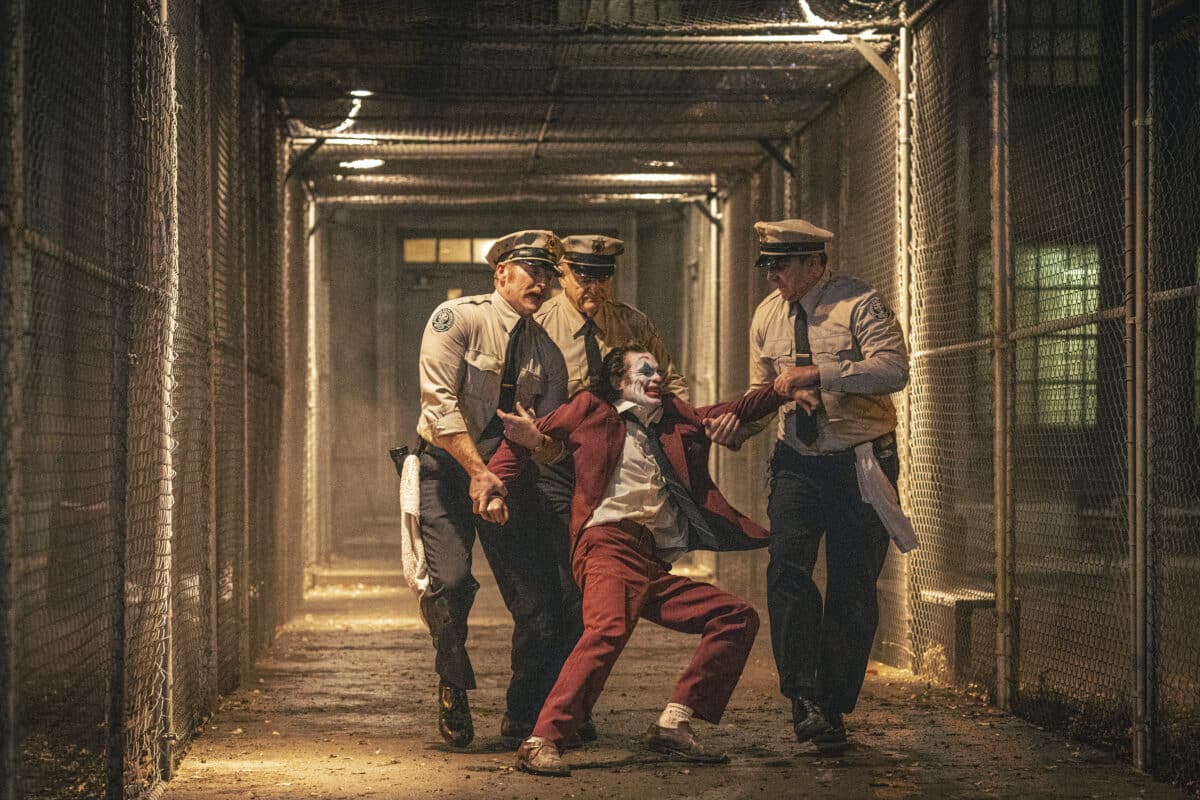 This image released by Warner Bros. Pictures shows Joaquin Phoenix, foreground center, and Brendan Gleeson, background center, in a scene from "Joker: Folie à Deux." (Niko Tavernise/Warner Bros. Pictures via AP)