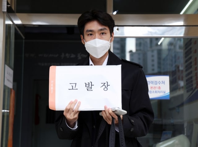 Lawyer Oh Jae-hyuk, representing the NewJeans fan group "Team Bunnies," holds up the complaint document to the press before entering the civil complaint office at Yongsan Police Station, in Seoul, to submit the documents, on Thursday. Image: Newsis via The Korea Herald